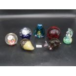 A quantity of paperweights including large red with bubbles, clear with dried flowers,