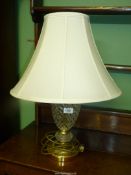 An electric cut glass and brass table lamp with cream shade.
