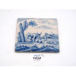A Dutch Delft tile painted in blue with a characterful cow in a landscape,
