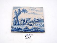 A Dutch Delft tile painted in blue with a characterful cow in a landscape,