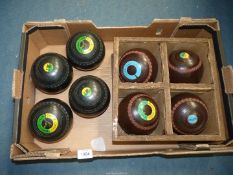 A set of brown Hemselite Championship bowls, size 5 in a rack and a set of black Hemselite bowls,