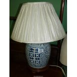 An Oriental blue and white ginger jar converted into a table lamp on wooden stand, with shade.