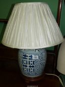 An Oriental blue and white ginger jar converted into a table lamp on wooden stand, with shade.