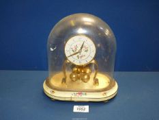 A German made Kan Anniversary clock, under glass dome on a metal painted stand,