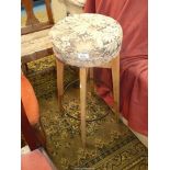 A circular upholstered seated high stool, the four splay feet united by a steel hoop,