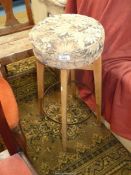 A circular upholstered seated high stool, the four splay feet united by a steel hoop,