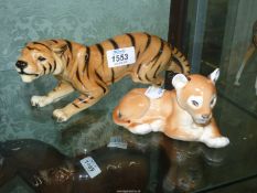 A china Tiger in a pouncing position and a Lion cub in a lying position.