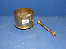 A brass Trench Art vase made from a Military shell standing on four legs with a brass pestle.