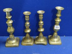 Two pairs of brass candlesticks with candle pushers, 9 1/4" tall and 8 1/4" tall.