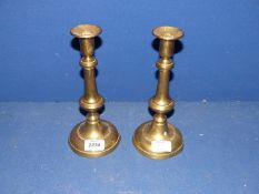 A pair of brass candlesticks with pusher.