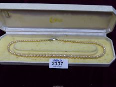 A string of simulated pearl with 925 clasp in the shape of a bow in a Lotus pearls presentation