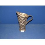 An Arts & Crafts style Pewter jug with all over inverted onion shaped stamp design,