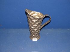 An Arts & Crafts style Pewter jug with all over inverted onion shaped stamp design,