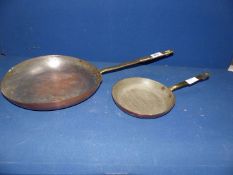 Two copper shallow pans with brass handles.