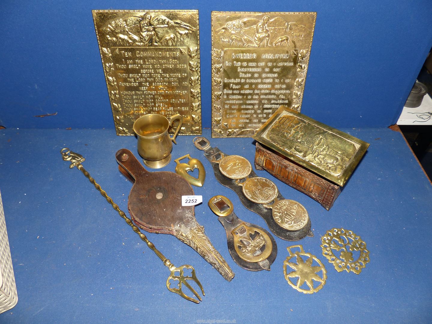 A small crate of brass items including plaques, horse brasses, tankard etc.