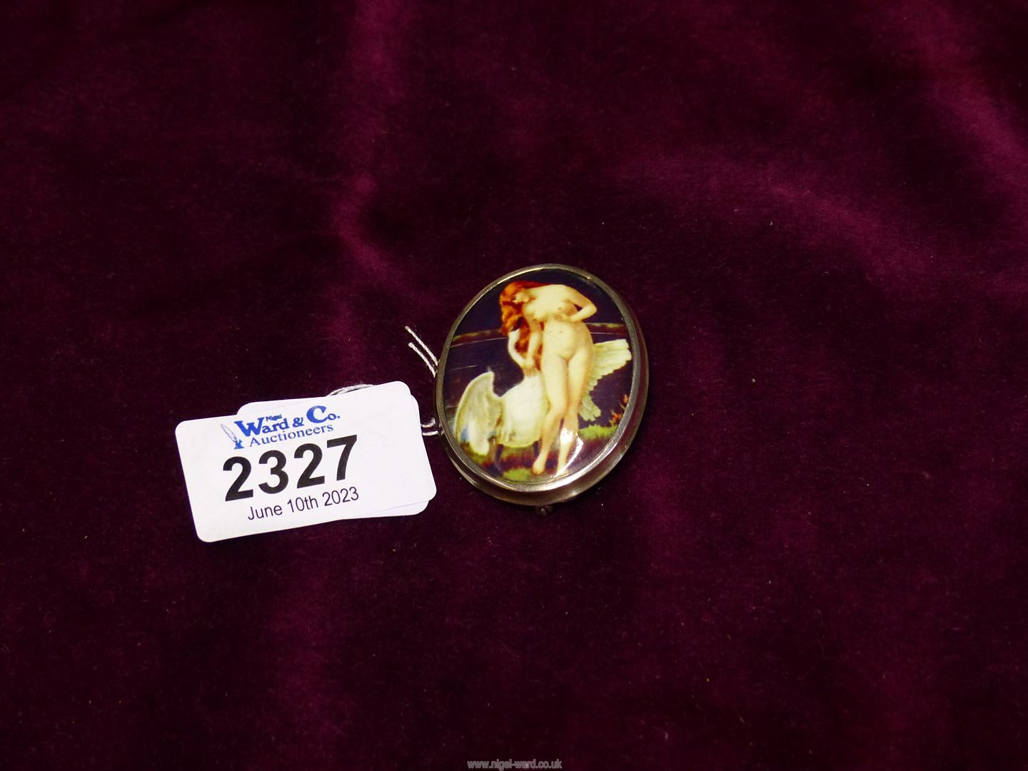 A brooch with miniature print of female nude on plastic and sterling silver mount.