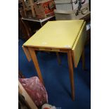 A yellow Formica drop leaf kitchen table with one drawer.