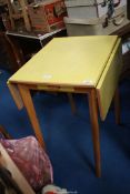 A yellow Formica drop leaf kitchen table with one drawer.