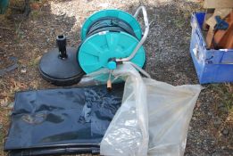 Black plastic sheeting, plastic stand and hose on a reel.