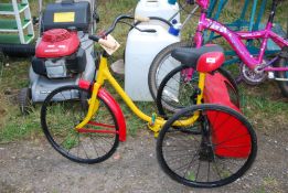 A child's trike painted yellow and red.