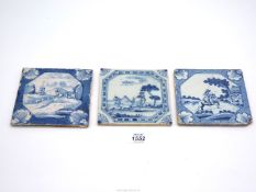 An English Delft landscape tile with powdered blue border and two other landscape tiles,