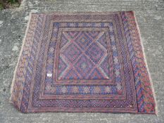 A Geometric patterned rug with squares of shades of red and blue, some fading, 45'' x 41 1/2''.