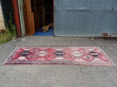A carpet Runner with hexagonal patterns in red and cream, some fading, 112'' x 41''.