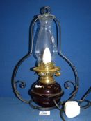 An oil lamp in wrought iron ceiling hanging frame with black glass reservoir, converted to electric.