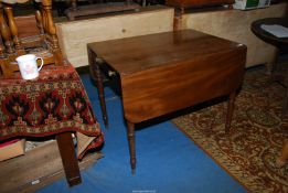 A Mahogany Pembroke Table standing on turned legs terminating in brass castors and having a drawer