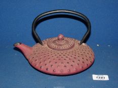 A heavy cast metal oriental Teapot in red with raised spot design.
