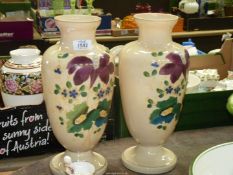 A pair of cream opaque glass vases having painted green leaves and purple flowers, chip to one,