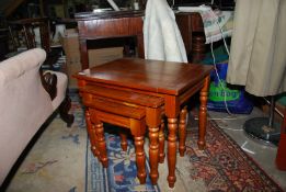 A contemporary honey Pine nest of three rectangular occasional Tables standing on turned legs,