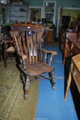 An Elm seated Windsor type Elbow Chair standing on turned legs and stretchers and with turned arm