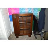 An unusual dark Oak Display Cabinet having a three pane door and standing on block feet,