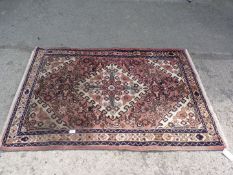 A small rug with central diamond motif in dusty red, brown and white, 60'' x 40 1/'2''.