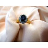 An 18ct gold ring set with large central black stone surrounded by twelve small diamonds, size L,