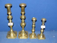 Two pairs of brass candlesticks on chamfered square bases, 11 3/4" and 7 1/4" tall.