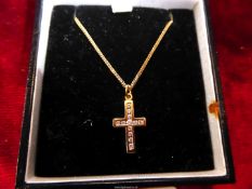 A yellow metal (unmarked gold?) pendant cross set with twelve white stones on a 9ct gold chain in