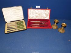 A cased set of butter knives, anti-pasti set, etc. and two brass candlesticks.
