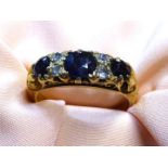 A stamped 18ct gold Engagement ring with three large dark blue sapphires and four diamond chips,