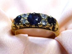 A stamped 18ct gold Engagement ring with three large dark blue sapphires and four diamond chips,