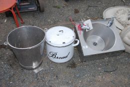 A small stainless sink unit with taps, enamel bread bin, and a stainless steel bucket.
