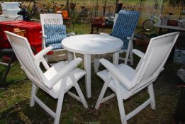 White plastic patio table with 4 folding chairs and 4 'fleur de lys pattern cushions.