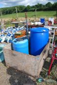 Two large blue plastic barrels, a rotary clothes line and a large wooden crate.