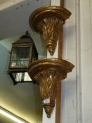 A pair of gilded semi-circular wall brackets/corbels having a gilt type finish and with foliage