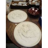 A pair of circular plaster plaques depicting cherubs, a/f, 20'' diameter.