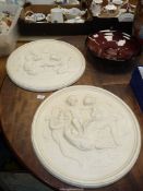 A pair of circular plaster plaques depicting cherubs, a/f, 20'' diameter.