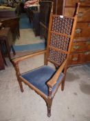 An arts and crafts design open-armed Elbow Chair having a black upholstered drop-in seat,