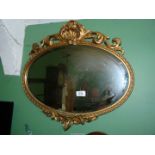 A pretty oval bevelled wall Mirror with gilt frame decorated with scrolling foliage and shells,