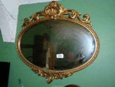 A pretty oval bevelled wall Mirror with gilt frame decorated with scrolling foliage and shells,